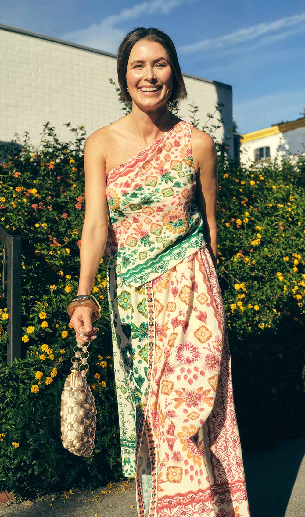 smiling woman in a printed one-shoulder dress in the sunshine