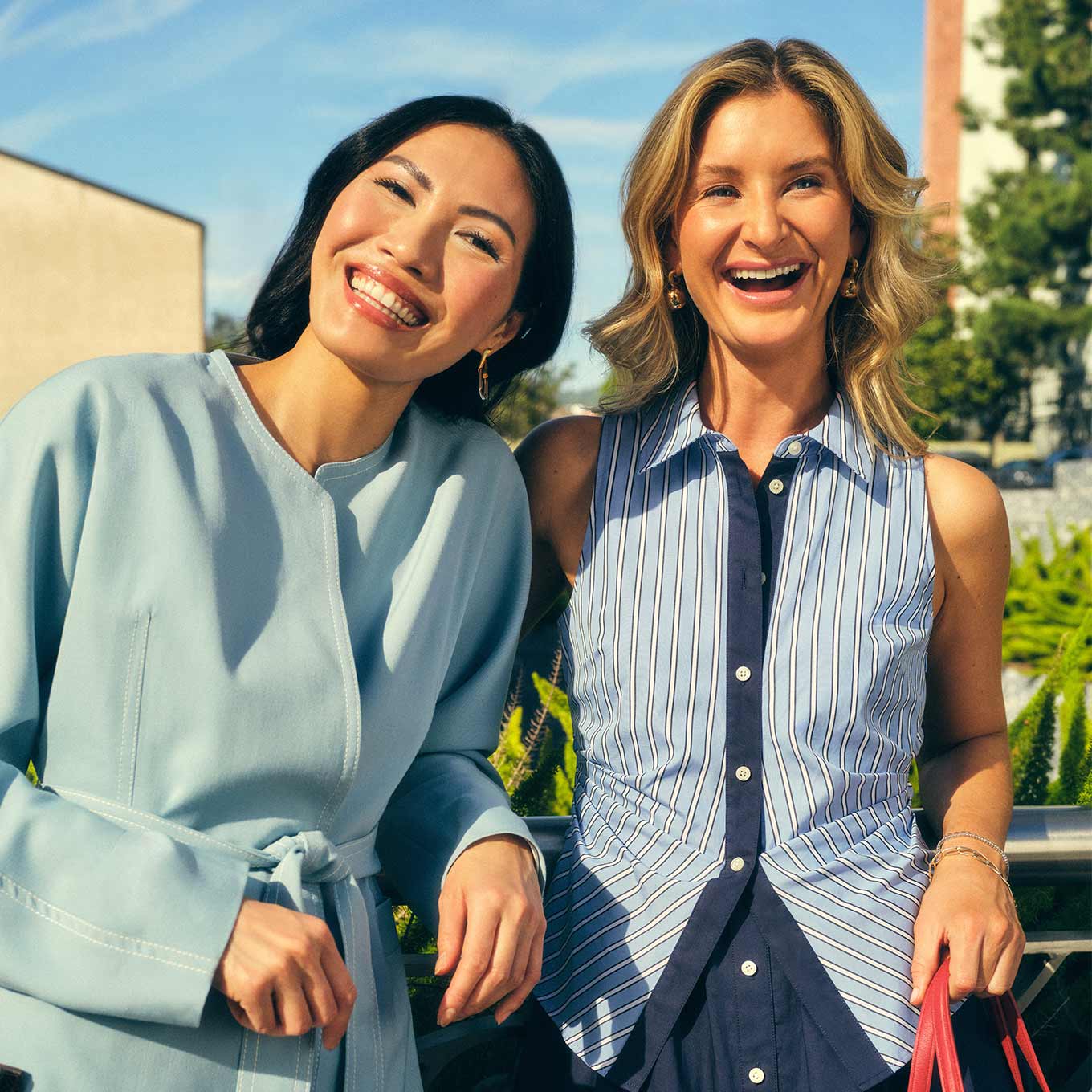 two women wearing polished blue tops and smiling in the sunshine